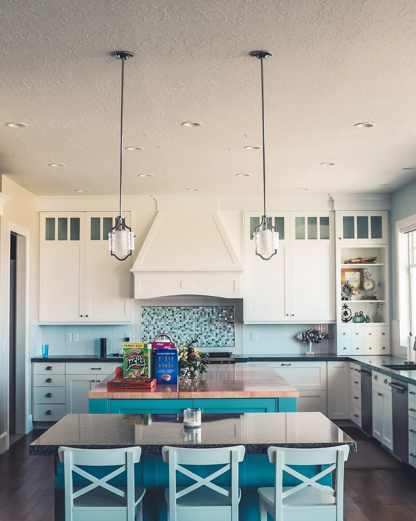 A bright white kitchen with a central island and counter stools