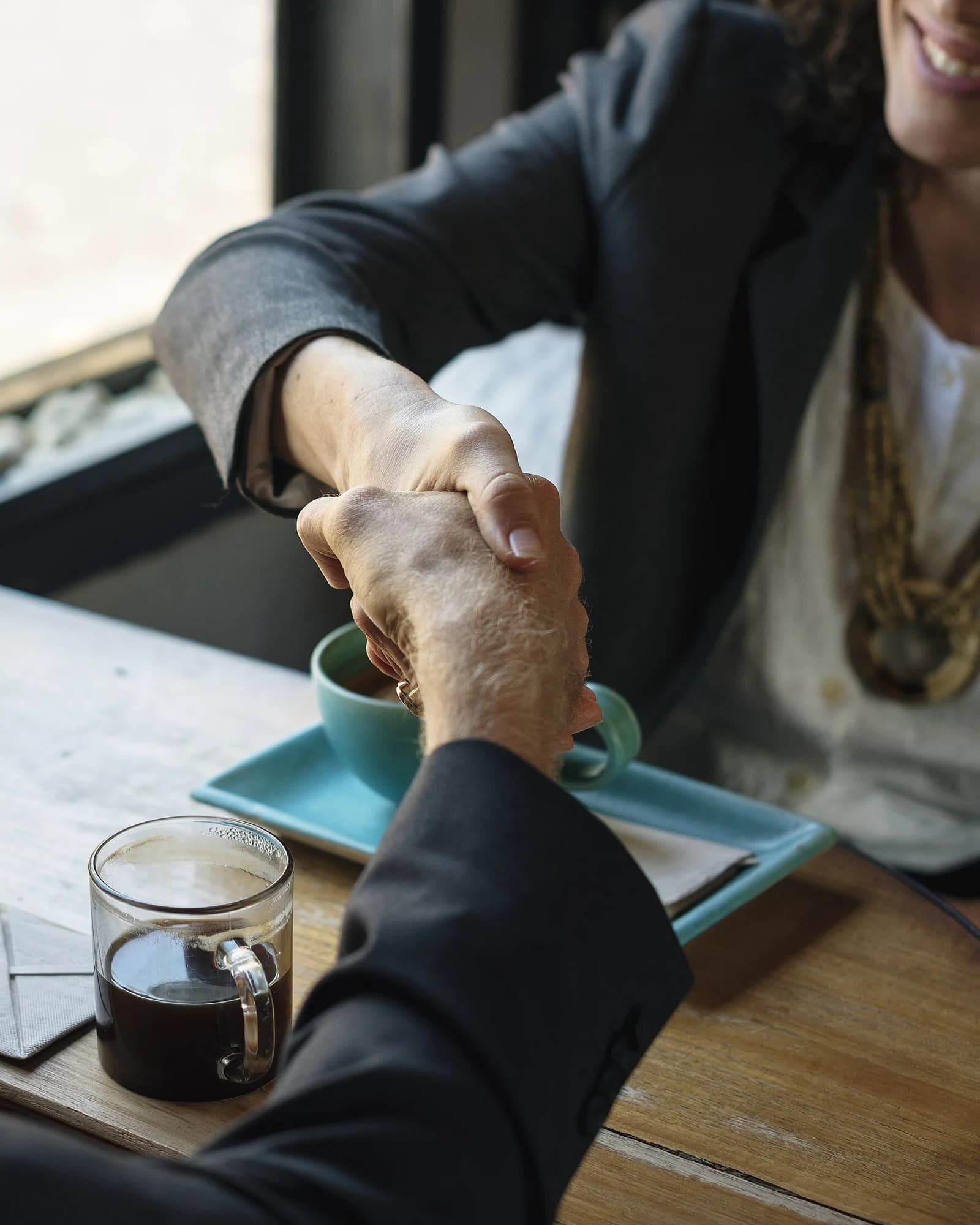 A contractor and a homeowner shaking hands over a signed agreement