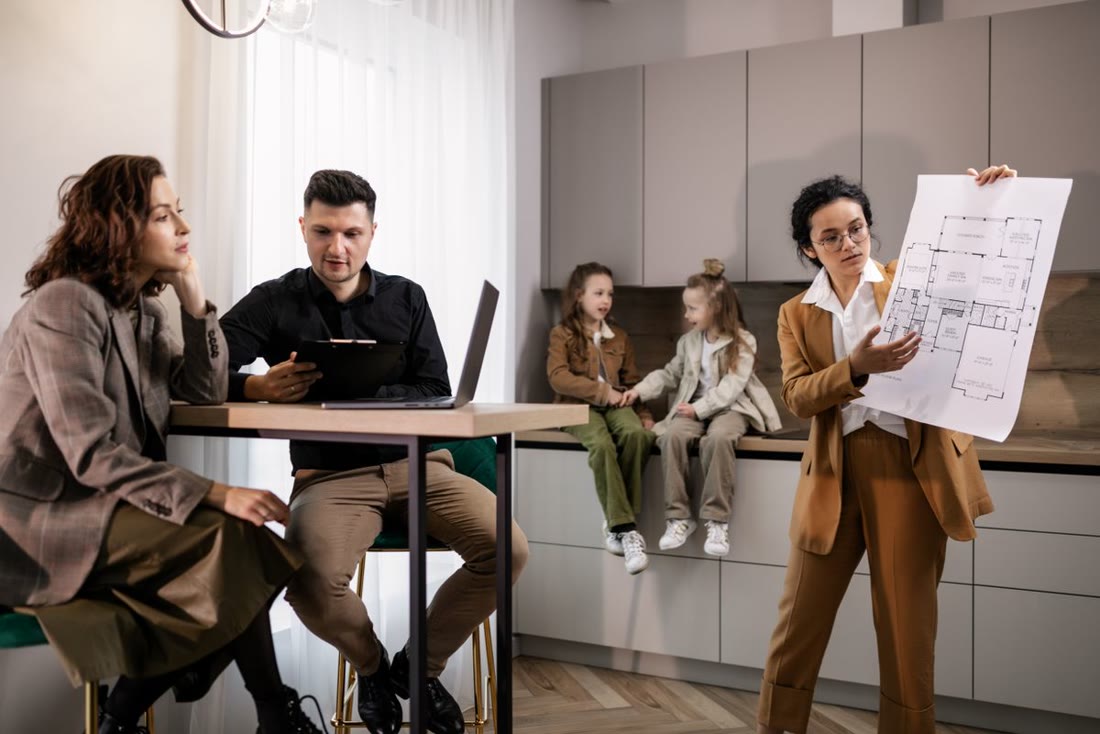 A designer presenting a home plan to a homeowner couple in a modern kitchen